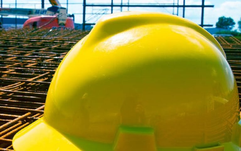 Yellow hard hat resting on rebar at a construction site